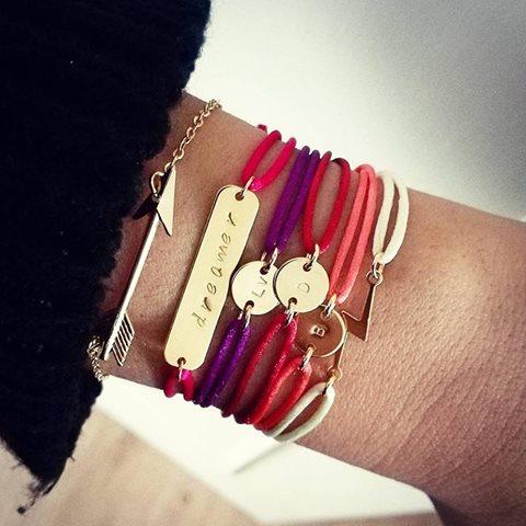 feerbeeld van de bliksem armband op de pols, gedragen door een vrouw met een eigenzinnige vintage hippie soul. De minimalistische gouden bedel schittert in het natuurlijke licht op het zwarte satin cord. Een sieraad voor degenen die liever de storm zijn dan de paraplu.