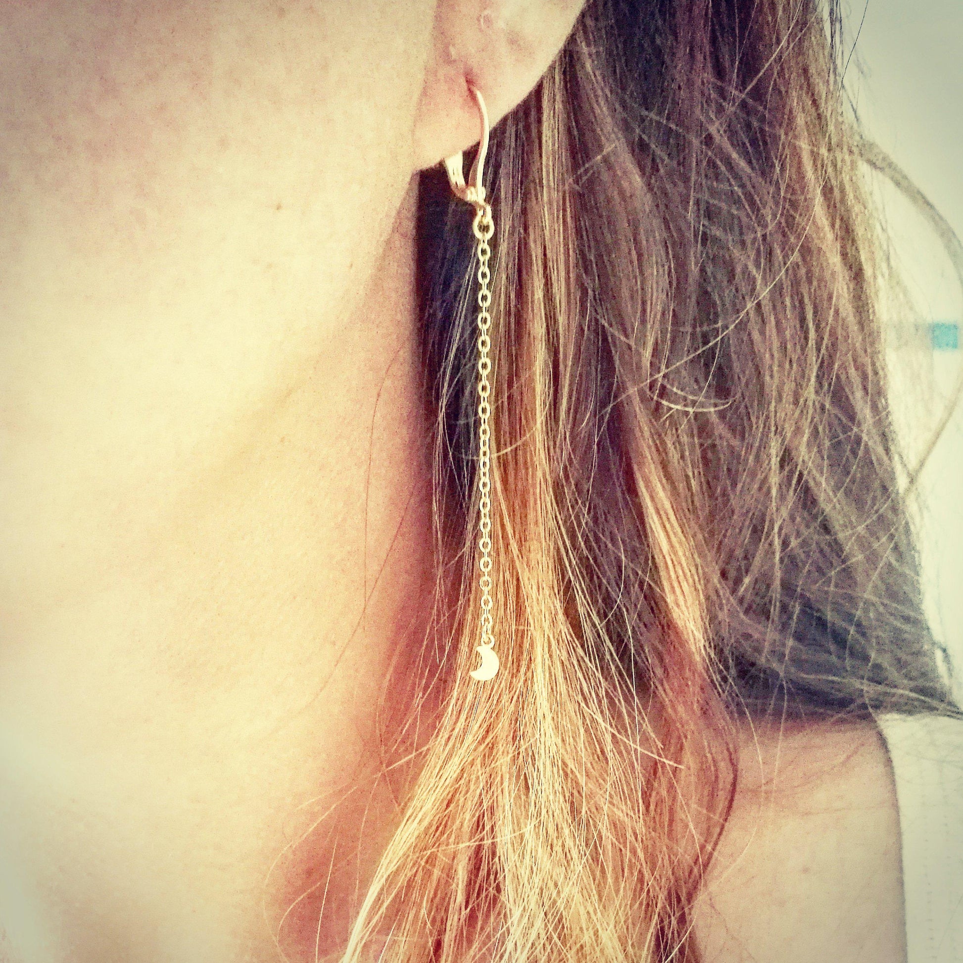 Vrouw draagt bungelende gouden maantjes in een earstack, vederlichte hangende oorbellen waar je mee kunt slapen zonder irritatie.