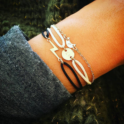 Vrouw met een eclectische stijl draagt de bliksem armband met satijnen koord; een symbool voor innerlijke kracht en een eigenzinnig karakter.