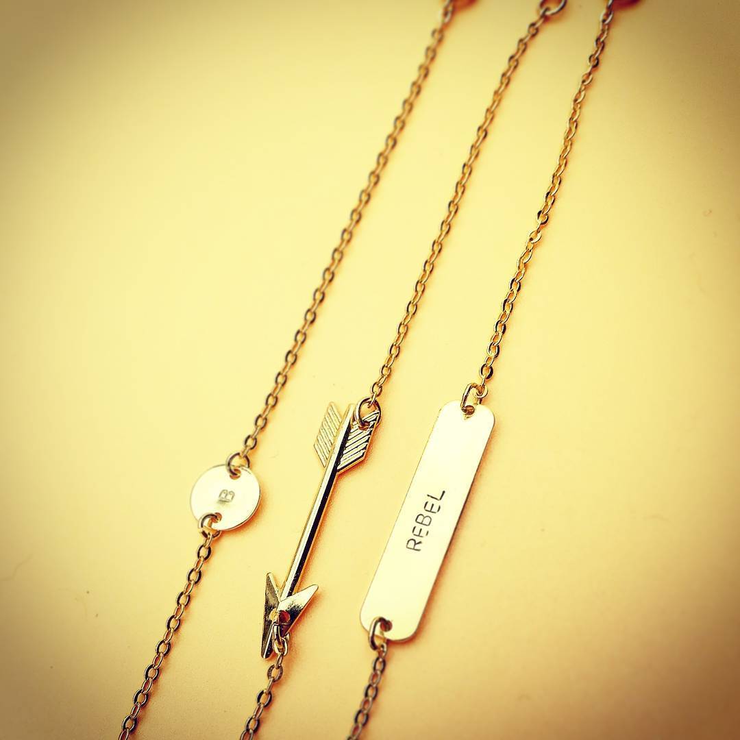 Layered look van de pijl ketting gecombineerd met een initiaal disk; chic-intellectuele stijl met een vintage hippie soul.