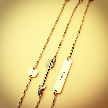Layered look van de pijl ketting gecombineerd met een initiaal disk; chic-intellectuele stijl met een vintage hippie soul.
